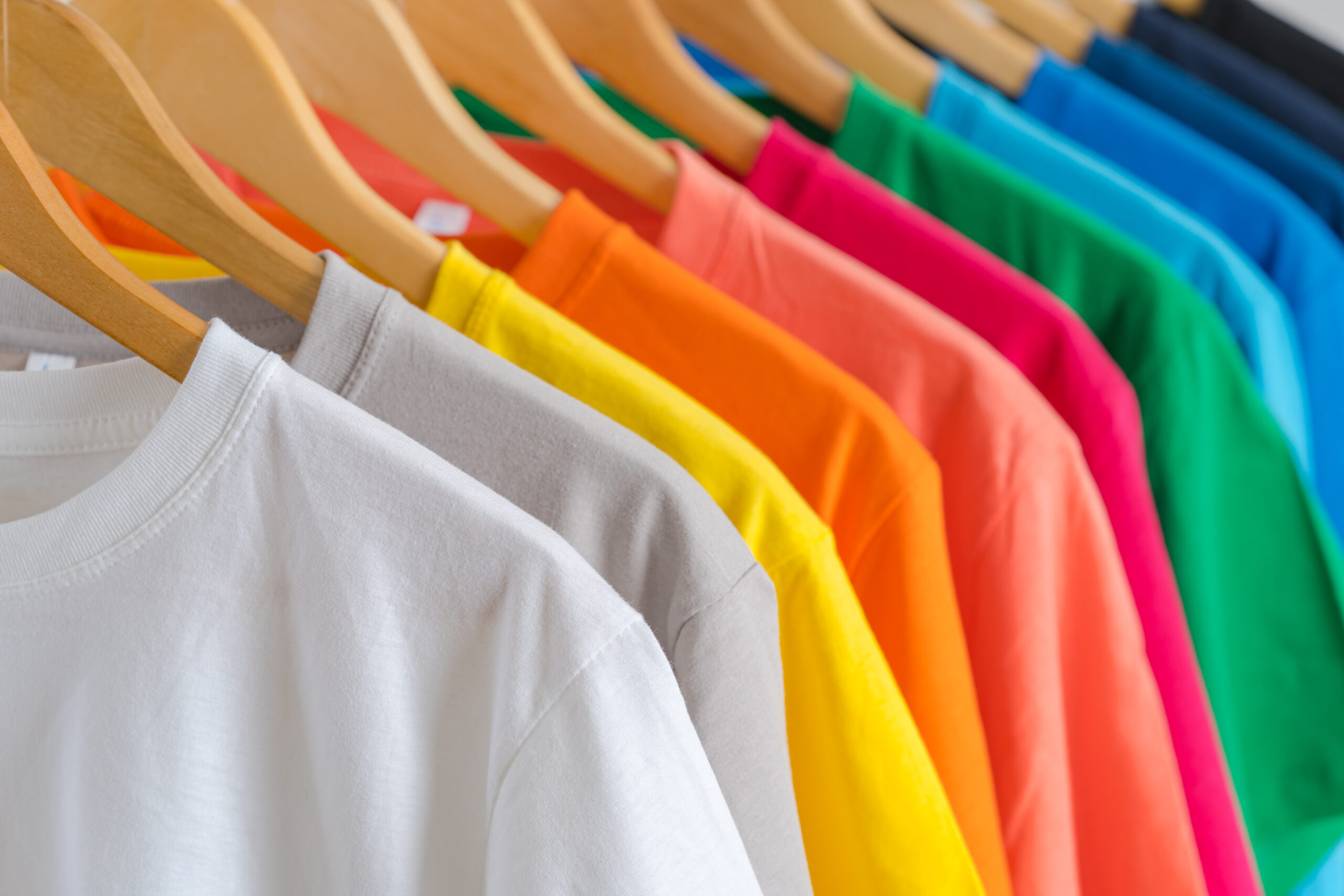 Cette image représente des t-shirts multicolores sur des cintres